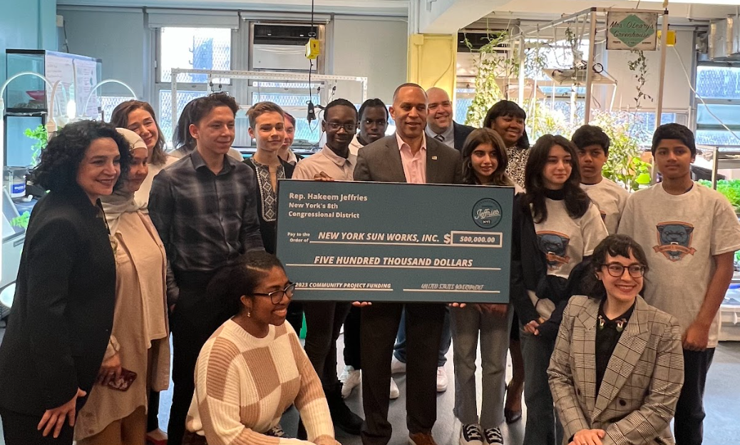 congressman hakeem jeffries holds a large check with students and NY sun Works leadership