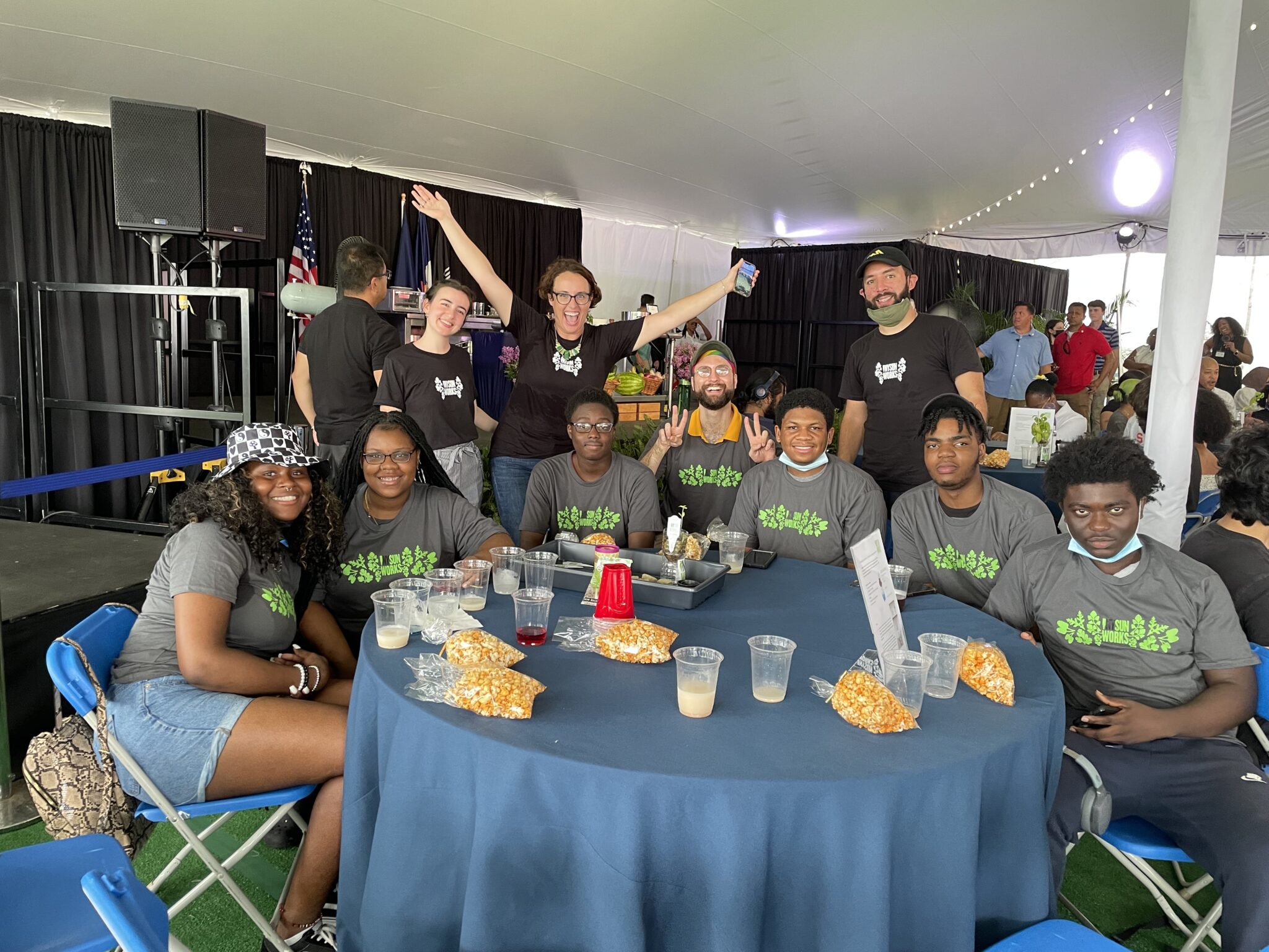 students sit around a table at gracie mansion wearing ny sun works t-shirts