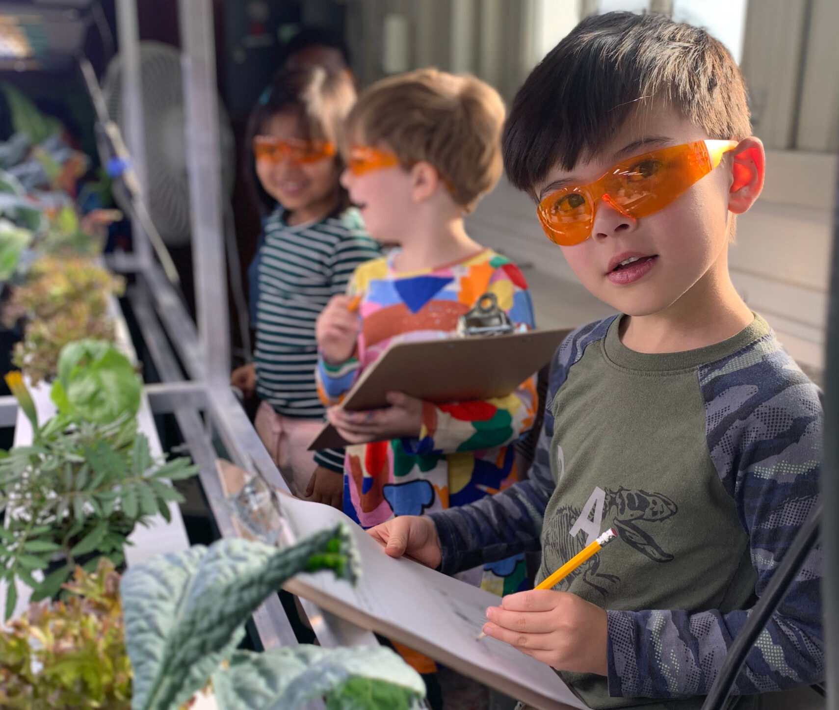 Children fill out information on clipboards.