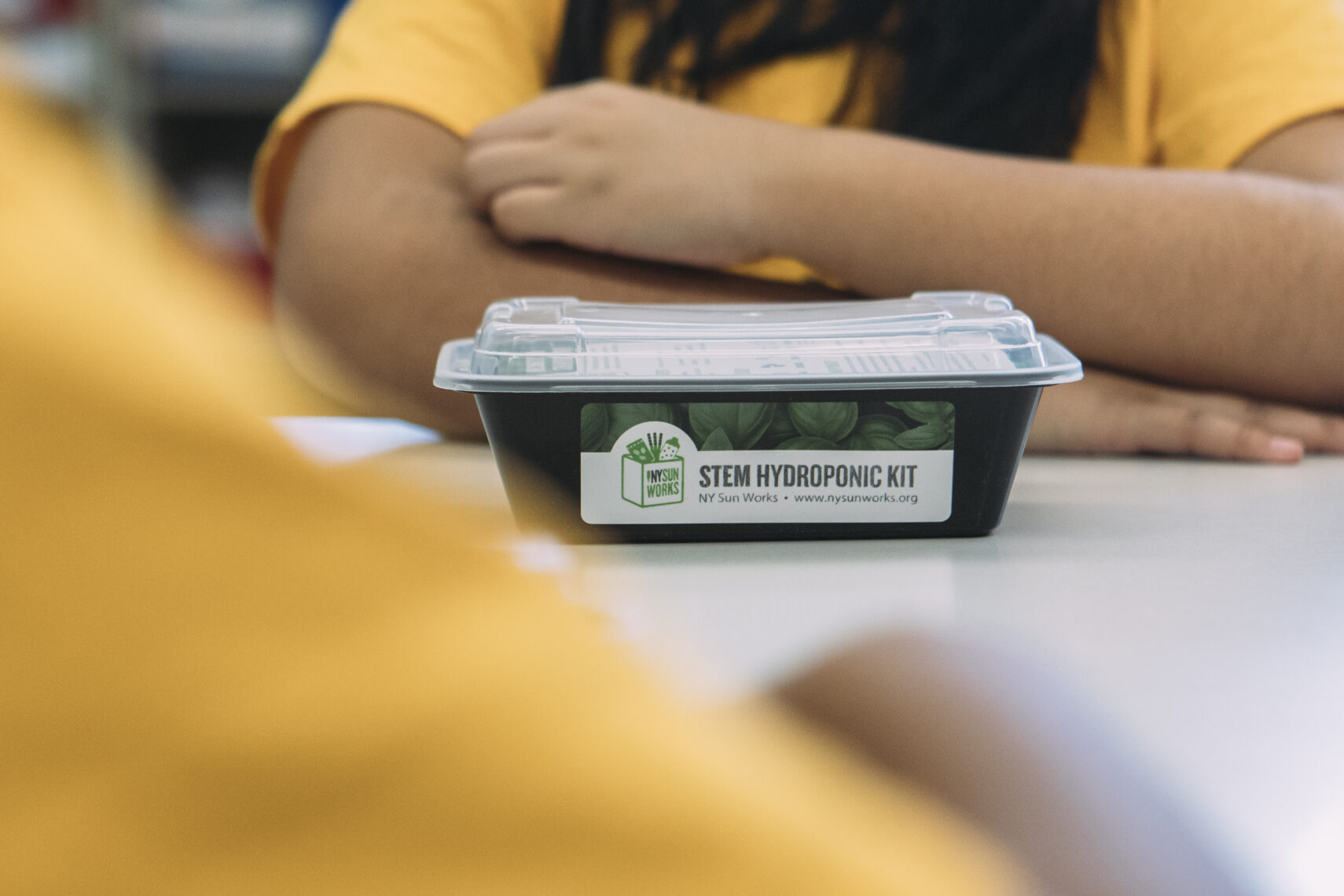 A child sits on a desk in front of a STEM Kit.