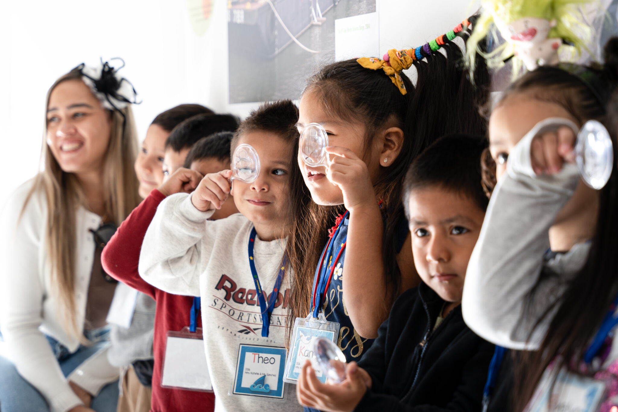 A class from Queens look through magnifying glasses at the NYSCI exhibit.