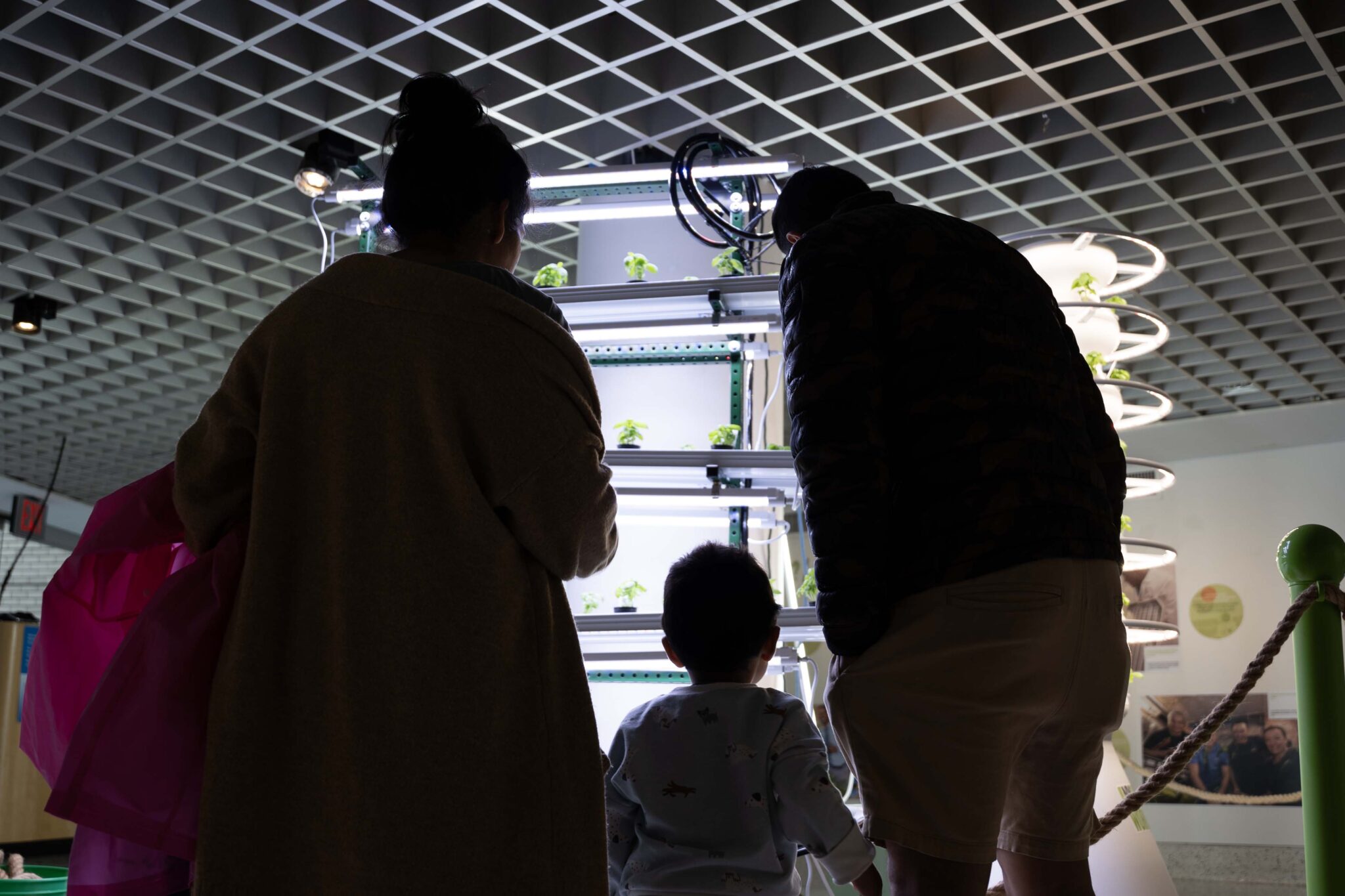 A couple and their children observe an NFT system at the NYSCI exhibit.